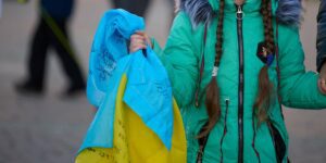 Ukraine, Kherson - November 14, 2022: Girl carries a yellow-blue Ukrainian flag autographed by soldiers, the day of the liberation of Kherson from Russian troops
